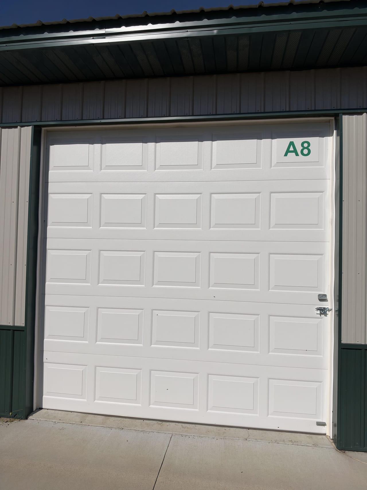 The closed white overhead door of large unit A8 on a concrete pad