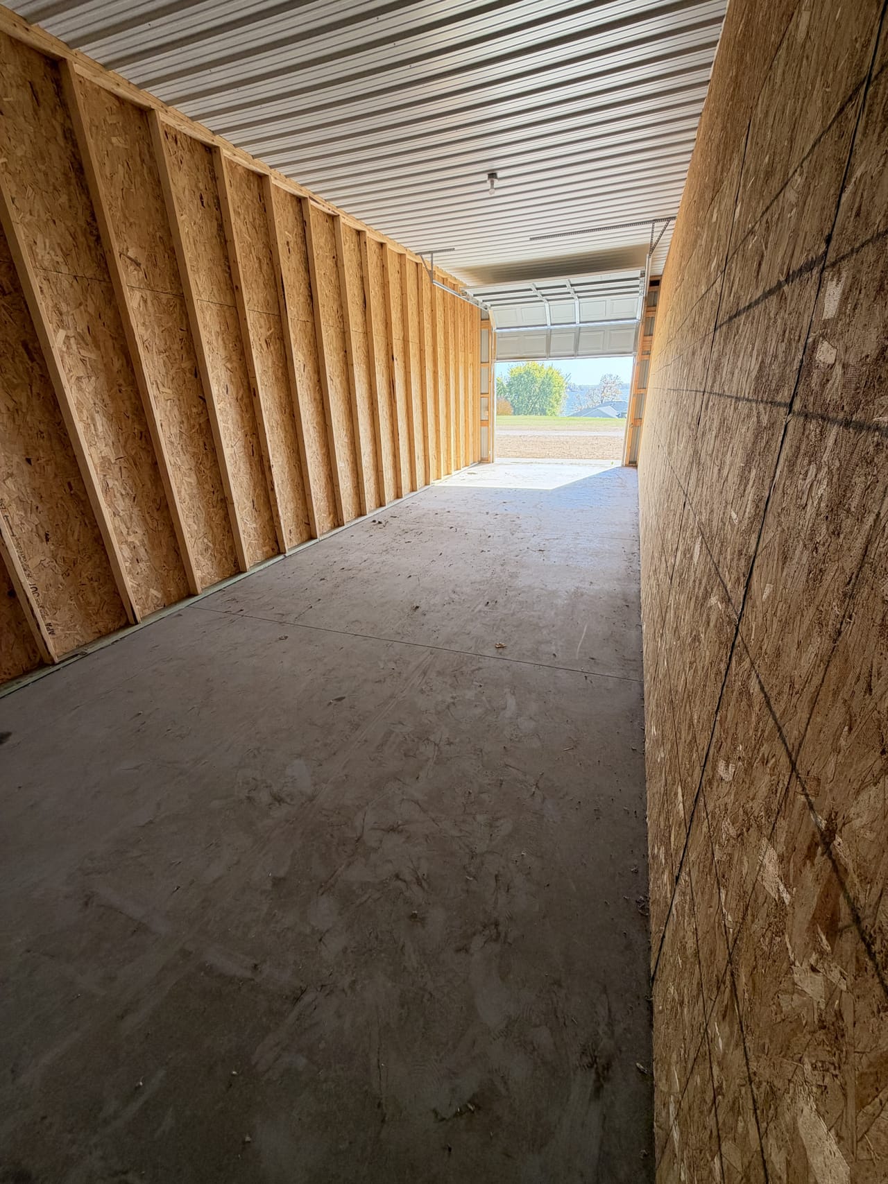 Inside a large unit looking out the open 10 x 10 door: 40 ft of concrete floor between plywood-lined walls