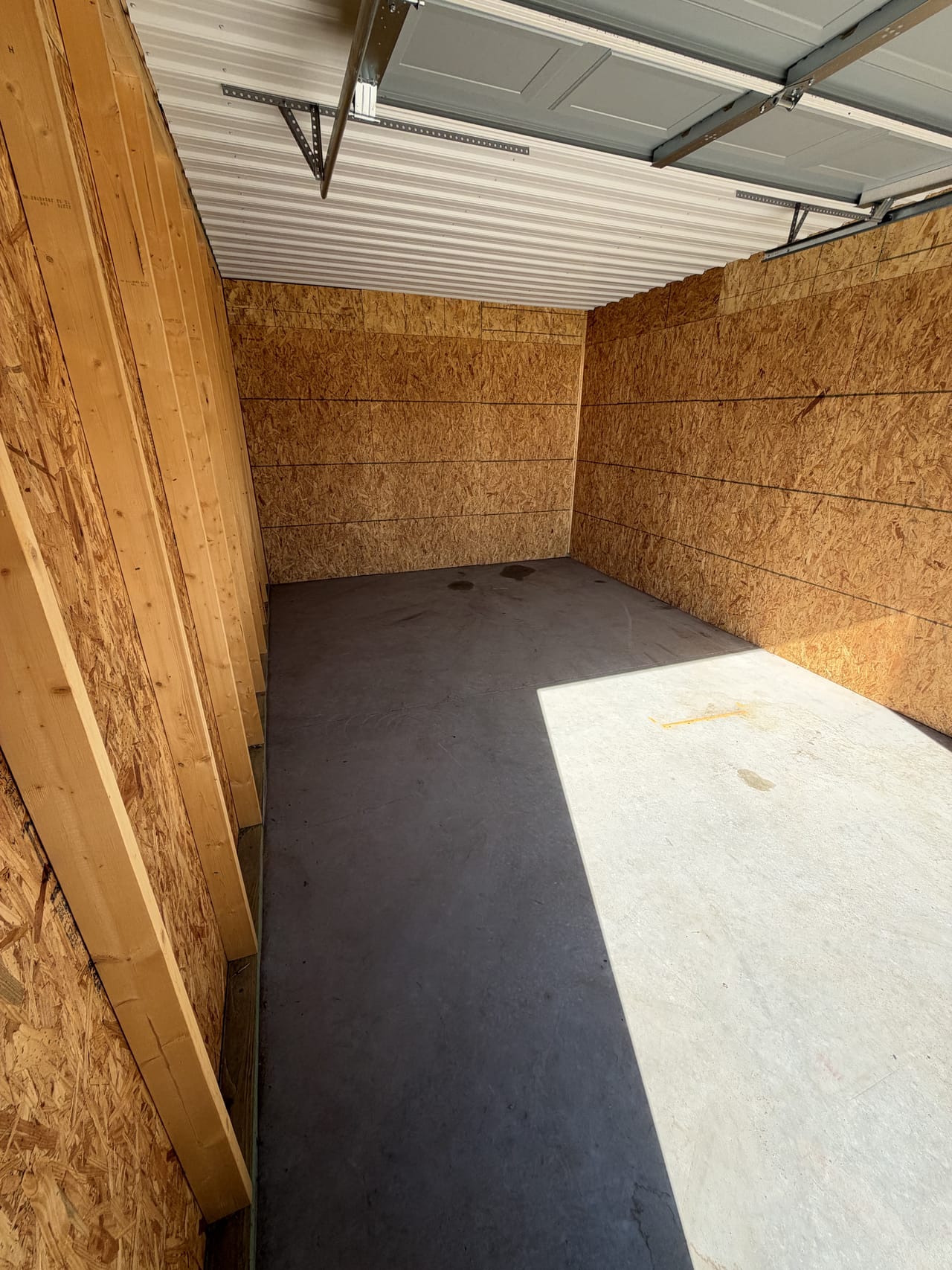 Inside an empty midsize unit: plywood-lined walls and a concrete floor